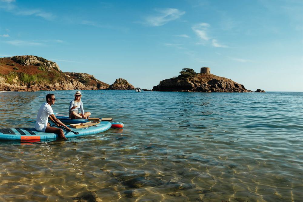 Two people eating pizza at Portelet Bay Jersey